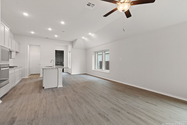 kitchen with white cabinets, a sink, a ceiling fan, and visible vents