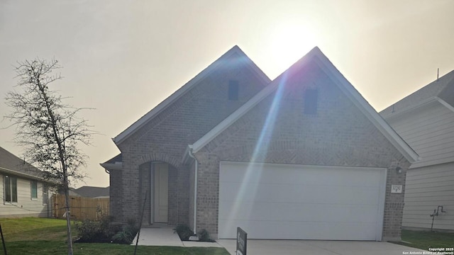 view of front facade featuring concrete driveway, brick siding, fence, and a front lawn