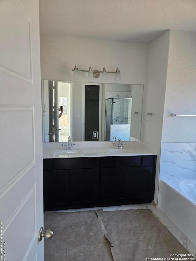 full bath featuring a bath, a stall shower, double vanity, and a sink