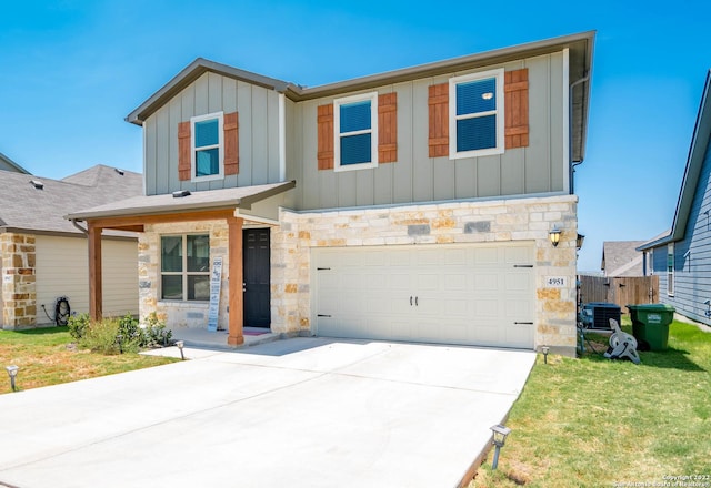 view of front of home with driveway, stone siding, a garage, and board and batten siding