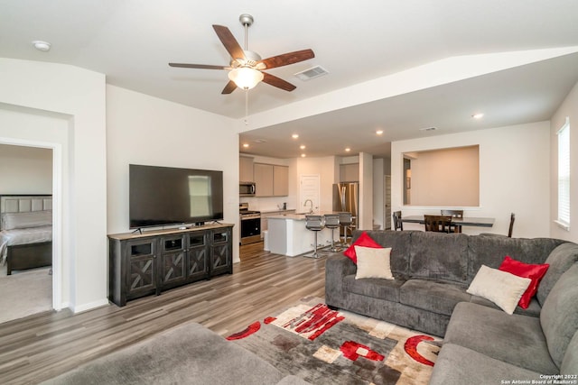 living area featuring lofted ceiling, visible vents, light wood-style floors, ceiling fan, and recessed lighting