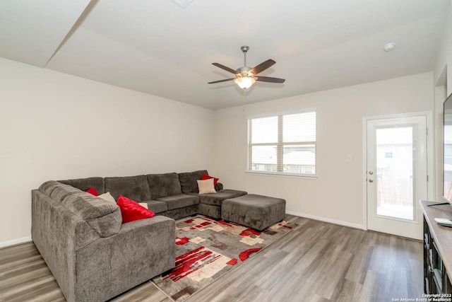living area with baseboards, wood finished floors, and a ceiling fan