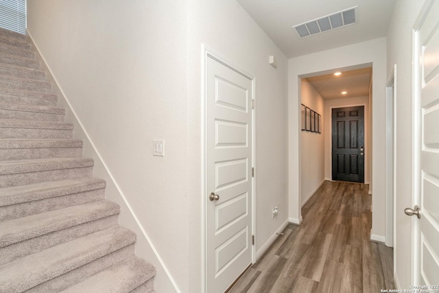staircase with wood finished floors, baseboards, and visible vents