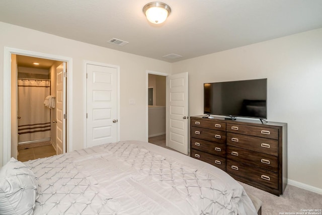 bedroom featuring light carpet, baseboards, ensuite bath, and visible vents