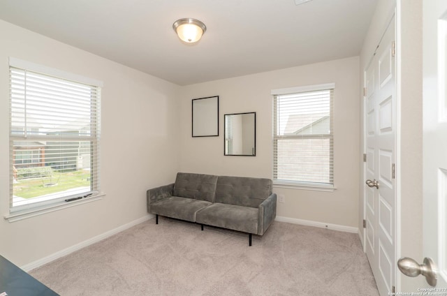 sitting room with baseboards and light colored carpet