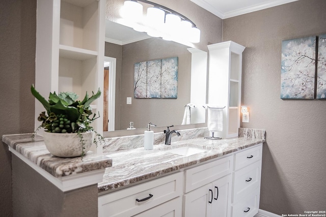 bathroom with a textured wall, vanity, and ornamental molding
