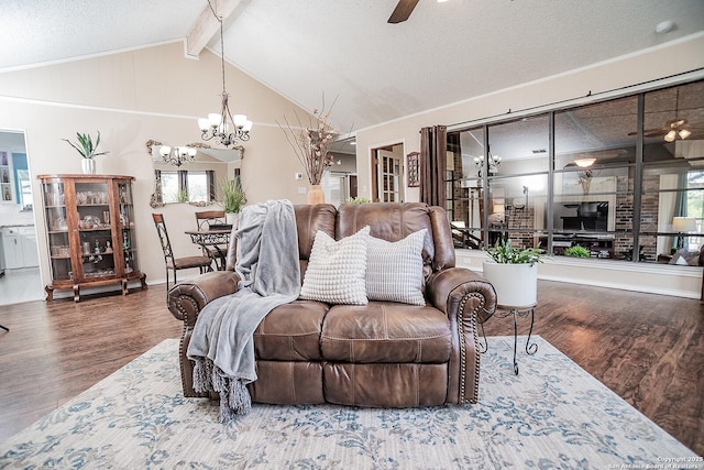 living area with ceiling fan with notable chandelier, vaulted ceiling with beams, a textured ceiling, and wood finished floors