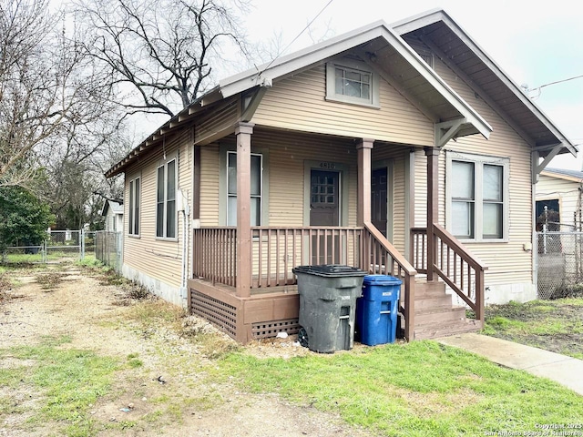 bungalow-style home with covered porch and fence