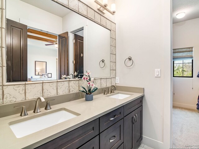 bathroom with baseboards, double vanity, a sink, and tasteful backsplash