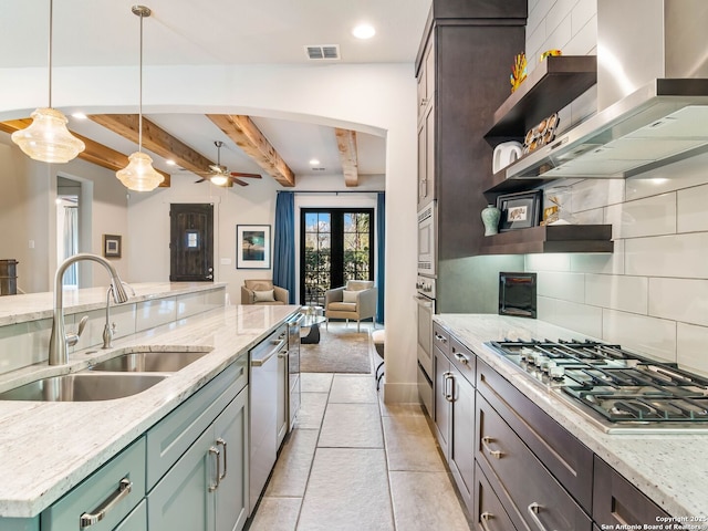 kitchen with a sink, open shelves, stainless steel appliances, wall chimney range hood, and visible vents