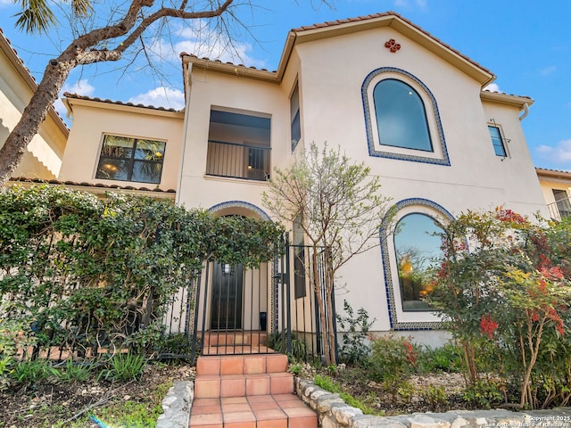 mediterranean / spanish house featuring stucco siding and a tile roof