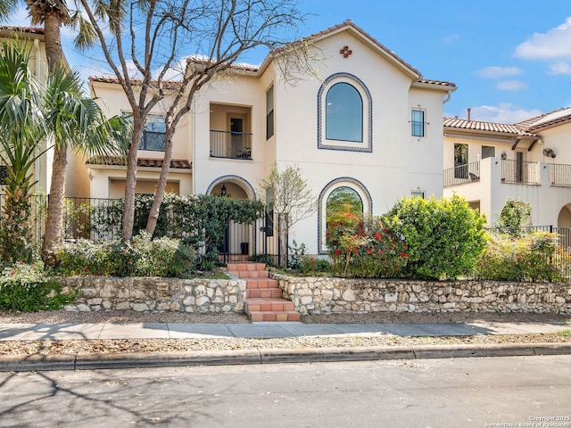 mediterranean / spanish home featuring a tile roof and stucco siding