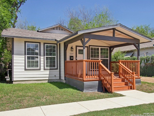 view of front of home with a front yard and roof with shingles