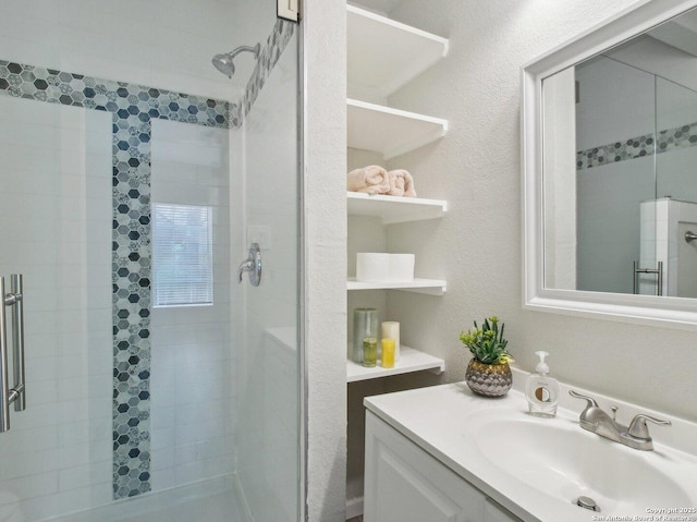 full bathroom featuring vanity, a textured wall, and a shower stall