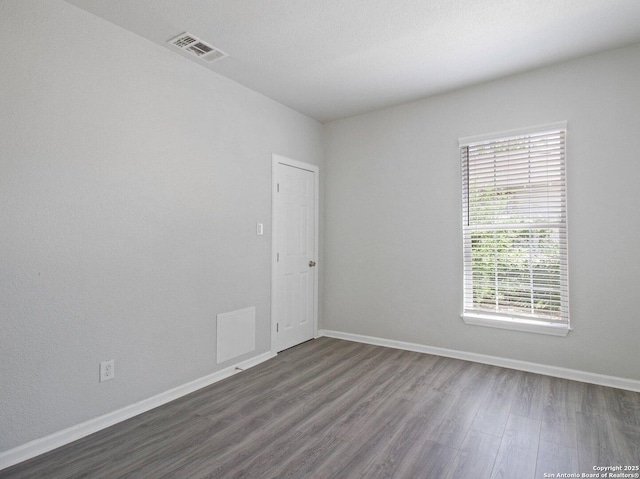 spare room with dark wood finished floors, baseboards, and visible vents