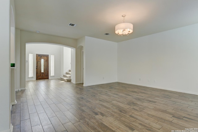 7609 Highland Park, San Antonio, TX 78250 - spare room with arched walkways, wood finished floors, stairway, and a chandelier