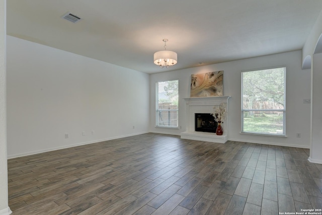 7609 Highland Park, San Antonio, TX 78250 - unfurnished living room featuring dark wood finished floors, a fireplace with raised hearth, baseboards, and a chandelier