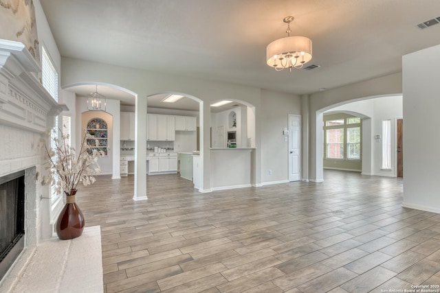 7609 Highland Park, San Antonio, TX 78250 - unfurnished living room with a chandelier, a fireplace, arched walkways, and light wood-style floors