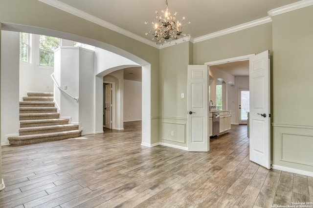 7609 Highland Park, San Antonio, TX 78250 - unfurnished dining area with arched walkways, light wood-type flooring, crown molding, a chandelier, and stairs