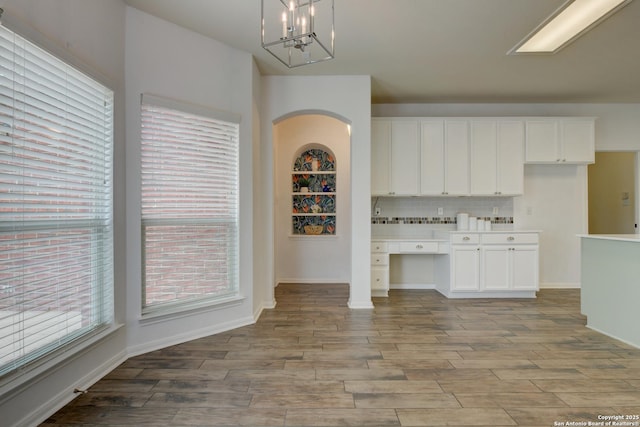 7609 Highland Park, San Antonio, TX 78250 - unfurnished dining area with light wood-style flooring, arched walkways, a chandelier, and baseboards