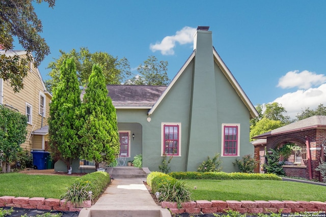 view of front of home with a front yard, stucco siding, and a chimney