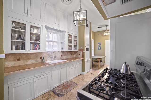 kitchen with glass insert cabinets, white cabinetry, stove, and decorative backsplash
