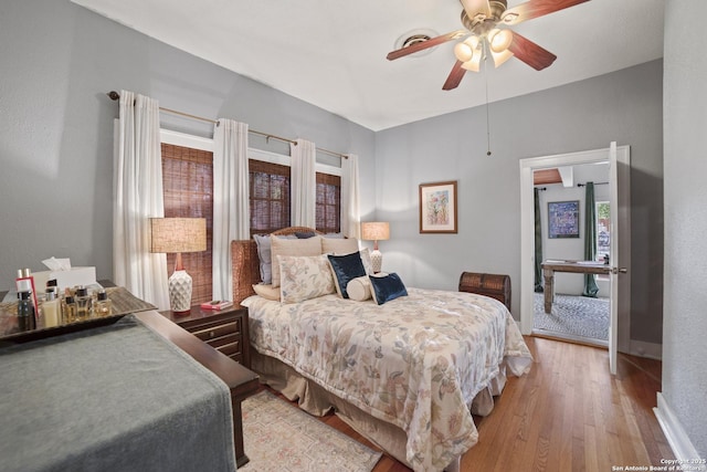 bedroom with a ceiling fan, baseboards, and light wood-type flooring