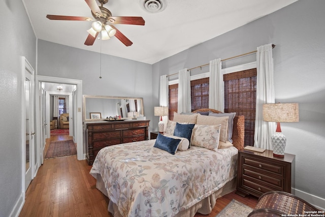 bedroom featuring baseboards, visible vents, wood finished floors, and ceiling fan