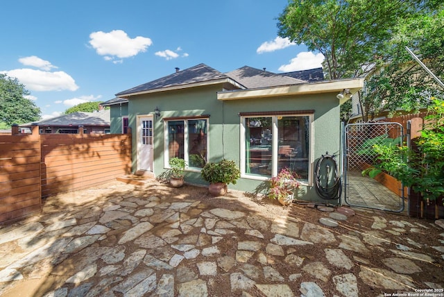back of property featuring stucco siding, fence, and a patio
