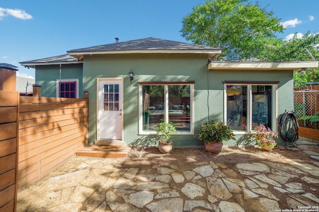 back of property featuring stucco siding and fence