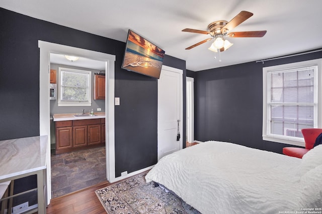 bedroom with baseboards, a sink, a ceiling fan, and dark wood finished floors
