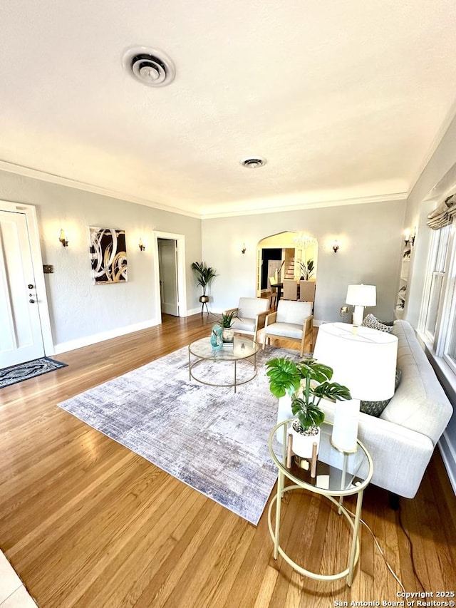 living room featuring ornamental molding, wood finished floors, arched walkways, and visible vents