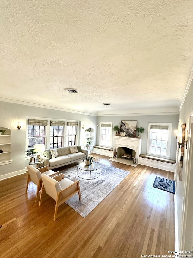 living room with plenty of natural light, ornamental molding, visible vents, and wood finished floors