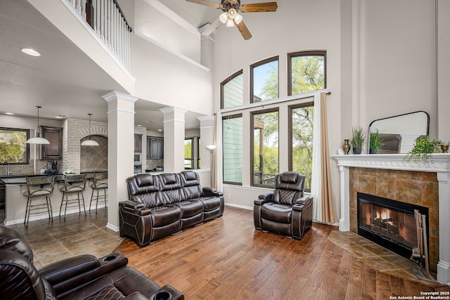 162 Teal Rdg, Canyon Lake, TX 78133 - living room featuring a tiled fireplace, ceiling fan, hardwood / wood-style flooring, and a healthy amount of sunlight
