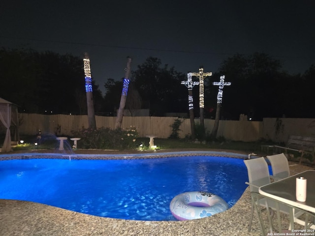 pool at twilight with a fenced backyard and a fenced in pool