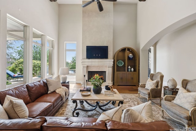 3919 El Chamizal, San Antonio, TX 78261 - living area featuring a ceiling fan, a fireplace, wood finished floors, arched walkways, and a towering ceiling