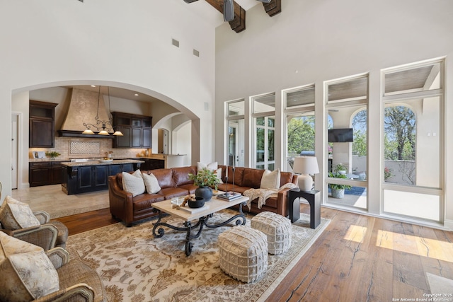 3919 El Chamizal, San Antonio, TX 78261 - living room with arched walkways, light wood-style floors, beamed ceiling, and visible vents