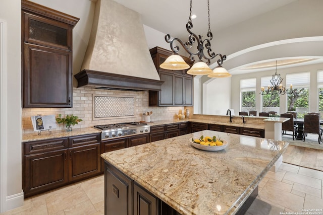 3919 El Chamizal, San Antonio, TX 78261 - kitchen featuring a notable chandelier, a sink, premium range hood, stainless steel gas stovetop, and decorative backsplash