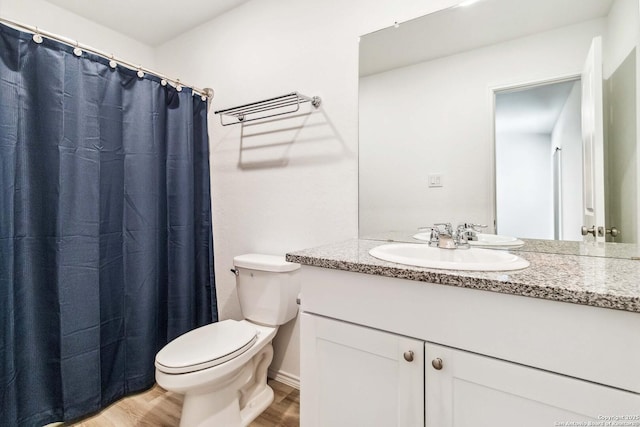 bathroom featuring a shower with curtain, toilet, wood finished floors, and vanity
