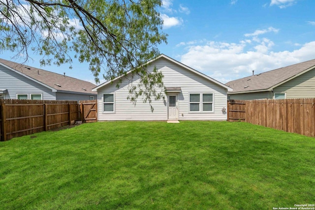 back of property featuring a fenced backyard and a yard