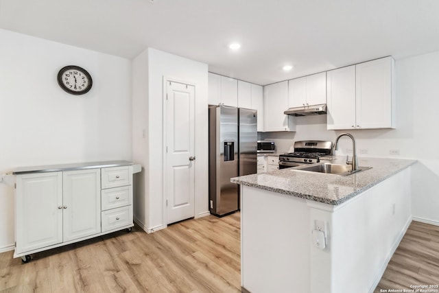 kitchen with a sink, a peninsula, under cabinet range hood, stainless steel appliances, and light wood-style floors
