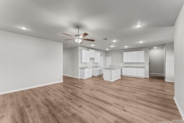 1542 Silver Run, New Braunfels, TX 78130 - unfurnished living room featuring light wood-type flooring, baseboards, a ceiling fan, recessed lighting, and a sink