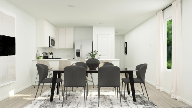 kitchen with white refrigerator with ice dispenser, white cabinetry, baseboards, and light wood-style floors
