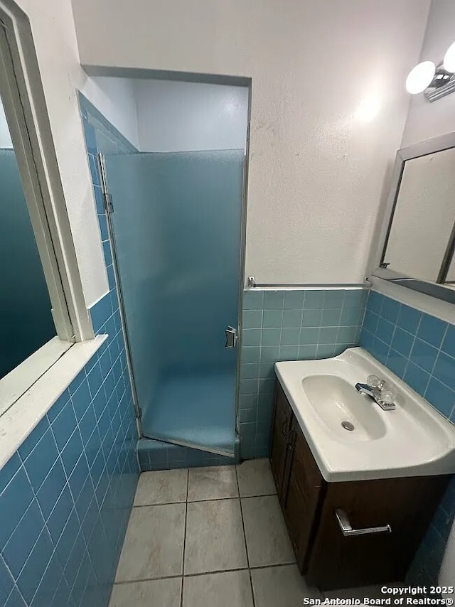 4223 Redstone Dr, San Antonio, TX 78219 - full bathroom featuring tile walls, a shower stall, tile patterned floors, vanity, and wainscoting