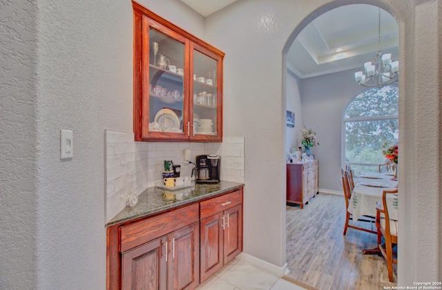 2110 Winding Vw, San Antonio, TX 78260 - bar featuring decorative backsplash, baseboards, arched walkways, a tray ceiling, and a notable chandelier