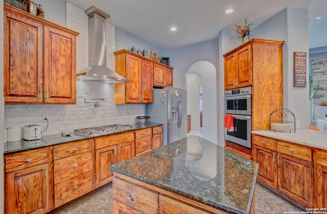 2110 Winding Vw, San Antonio, TX 78260 - kitchen featuring wall chimney range hood, brown cabinetry, arched walkways, and stainless steel appliances