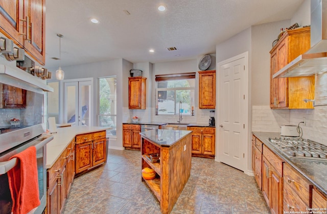 2110 Winding Vw, San Antonio, TX 78260 - kitchen with stainless steel gas cooktop, a center island, decorative backsplash, wall chimney range hood, and brown cabinets