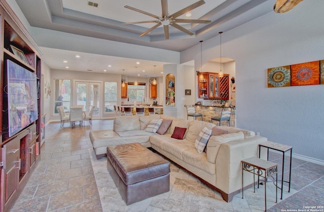 2110 Winding Vw, San Antonio, TX 78260 - living room featuring a tray ceiling, baseboards, a towering ceiling, ceiling fan, and stone tile flooring