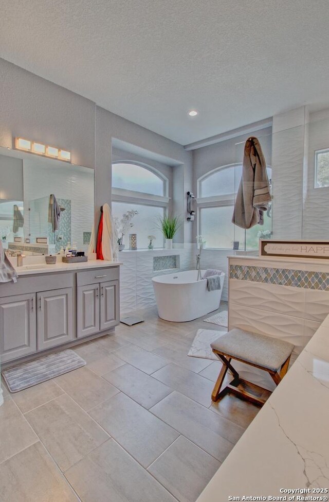 2110 Winding Vw, San Antonio, TX 78260 - bathroom with vanity, a freestanding tub, walk in shower, and a textured ceiling