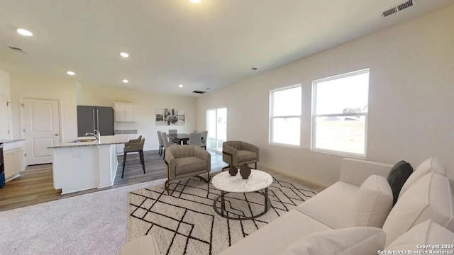 living room featuring baseboards, visible vents, light wood-type flooring, and recessed lighting